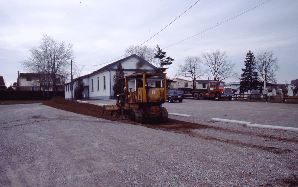 A bulldozer begins removing gravel and dirt from a parking lot Brick Street Church Excavation - 1989