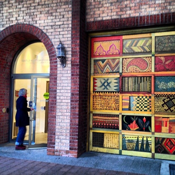 Front door of the Textile Museum of Canada with a series of 18 art panels in a display to the right of the doorway.