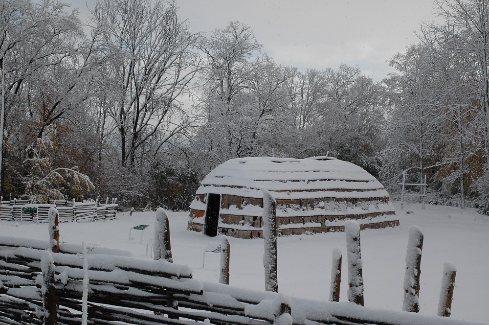 A snow-covered longhouse is visible in this 2008 image. The foreground maze is also covered in snow as are the trees in the background