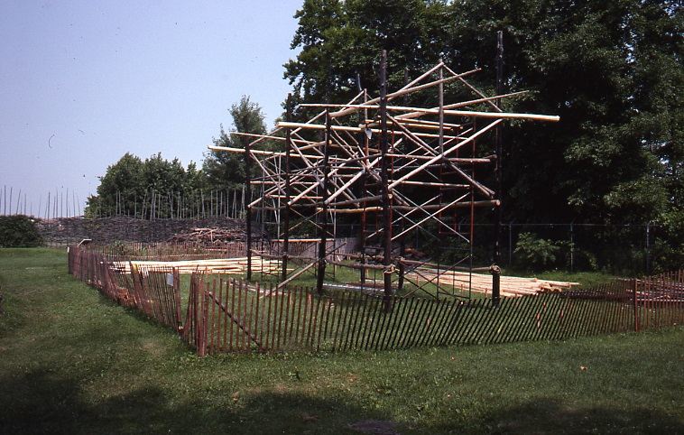 A log and metal frame is visible during the 1991 reconstruction of the Lawson Site longhouse.