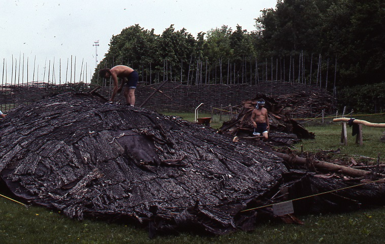 Two workers sift through a pile of bark siding debris after the demolition of the Lawson Site's original longhouse