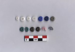 13 button artifacts arranged by colour. A 5 cm scale bar is shown below.