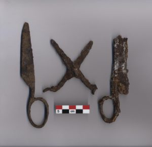 Three fragmentary scissor artifacts, rusted. A scale bar is shown beneath.