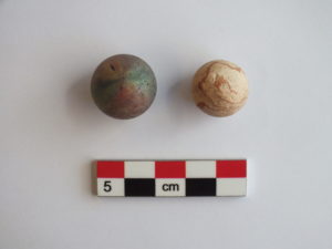 Two historical marbles, one metal and one clay. A scale bar is shown below.