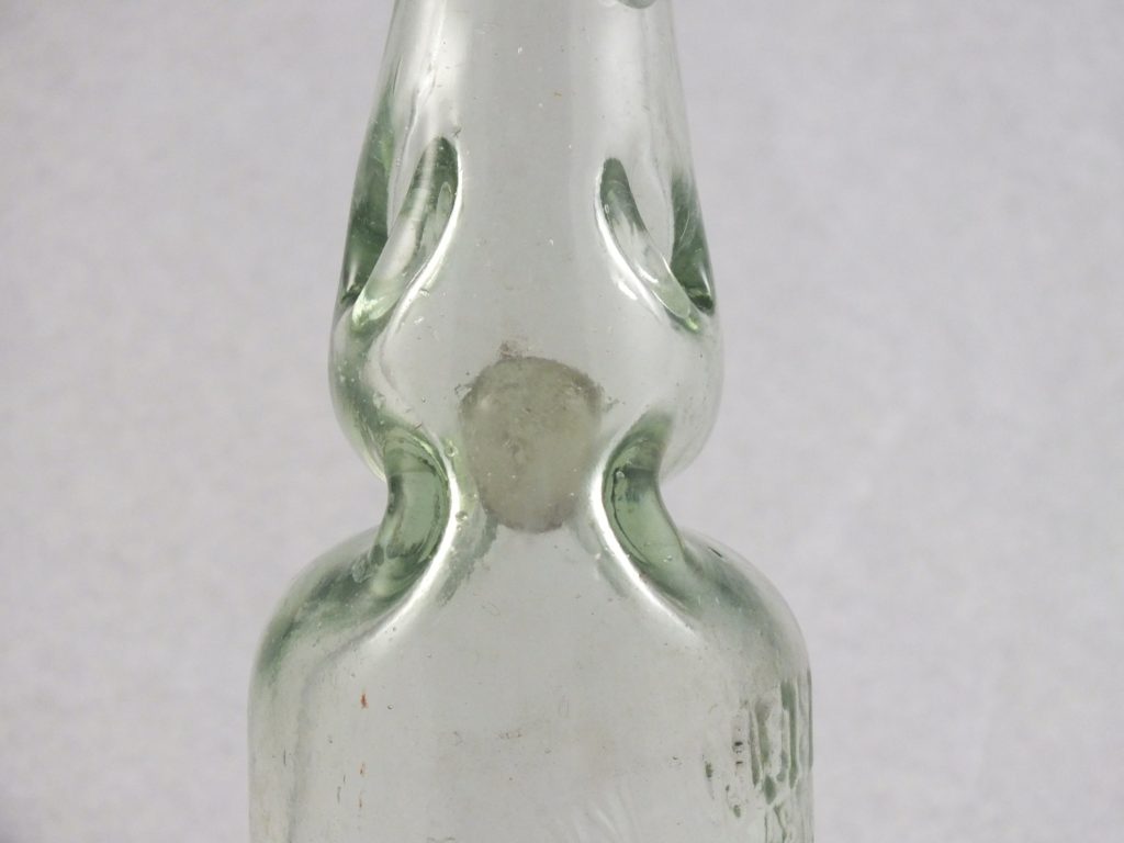 A close-up of a Codd Bottle artifact showing the narrow neck and glass bead inside.