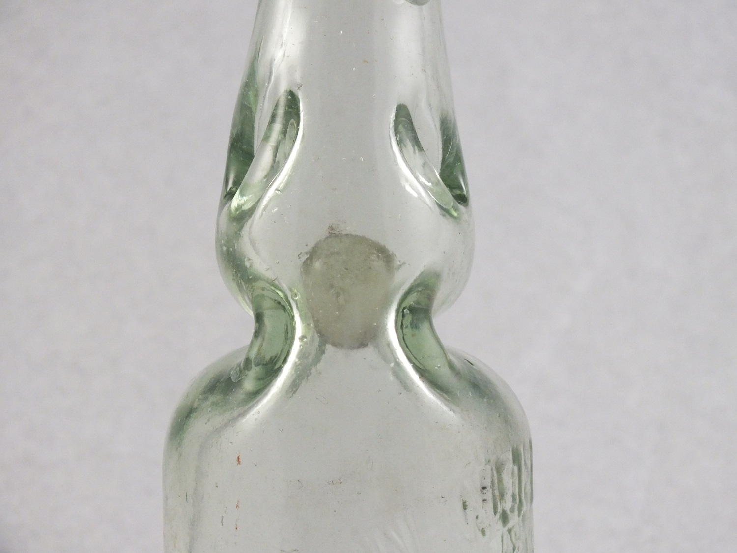 A close-up of a Codd Bottle artifact showing the narrow neck and glass bead inside.