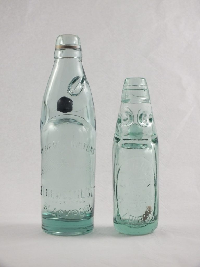 Two Codd Bottles side-by-side, one has a bead still inside the neck