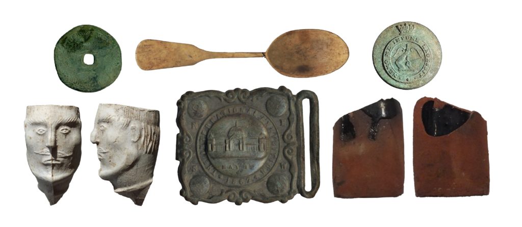 A series of historic artifacts including an effigy pipe, Chinese coin, spoon, engraved button, bottle, and engraved buckle